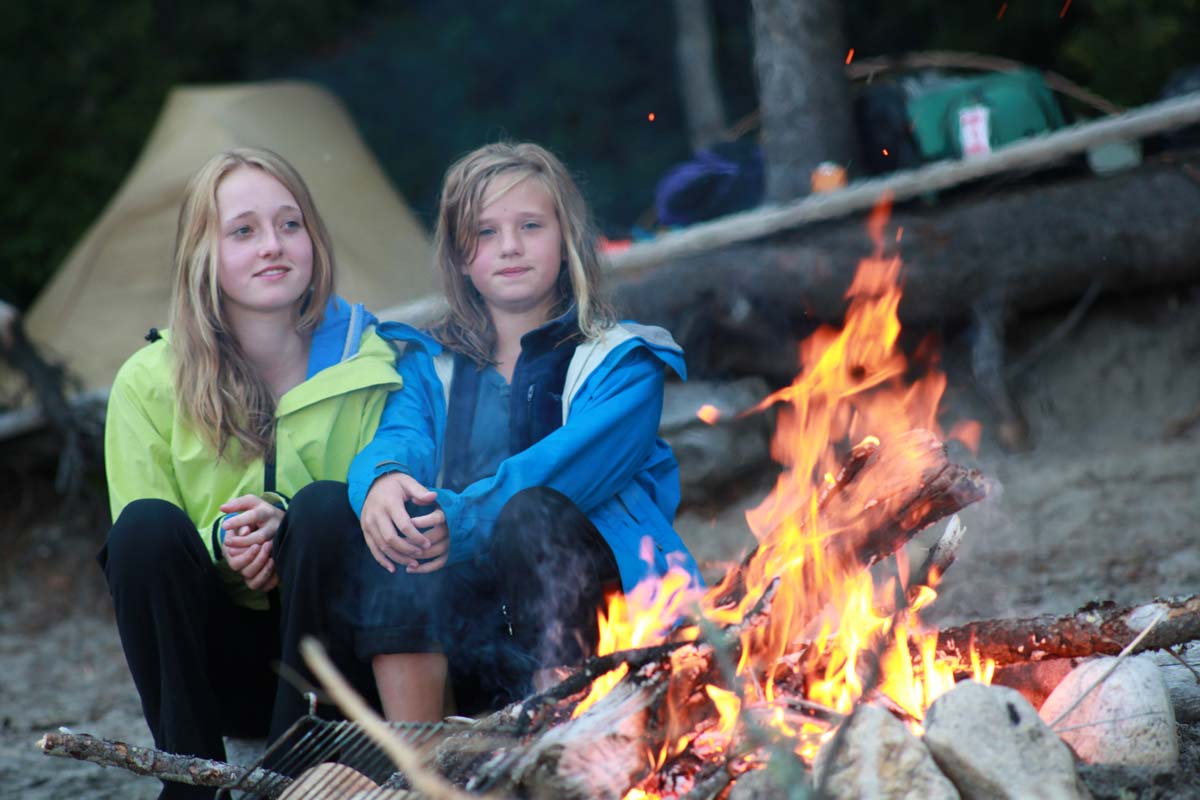 Two girls sitting by campfire